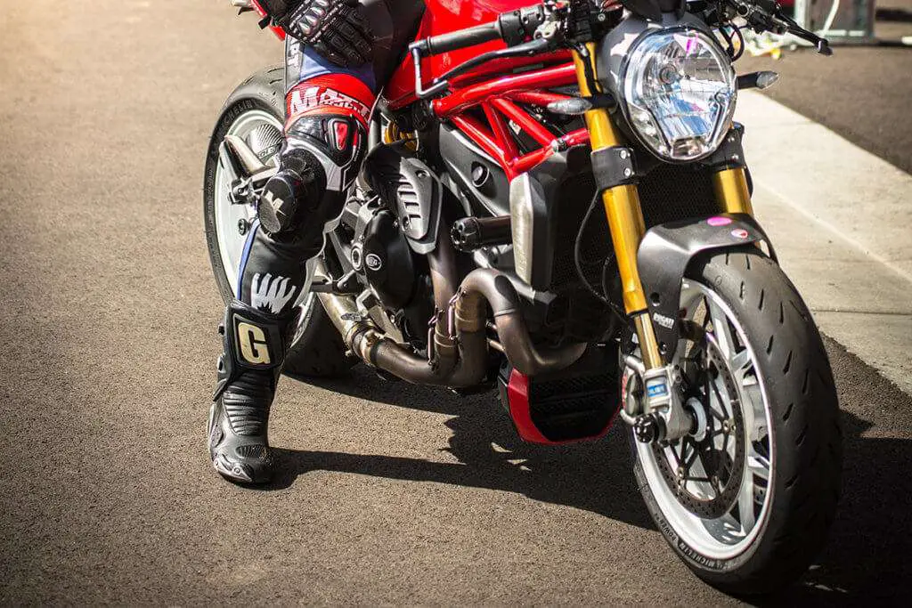 Person wearing racing shoes on a red motorcycle