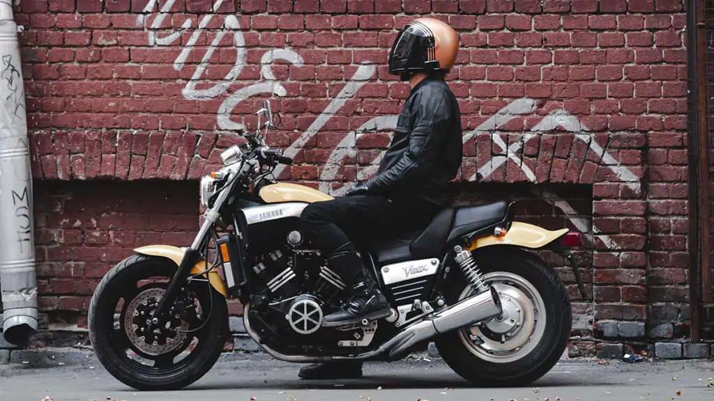 Person wearing motorcycle black boots on a yellow motorcycle