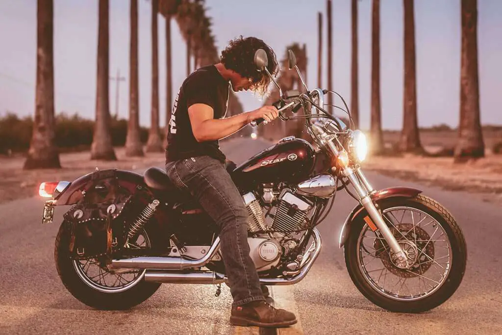 Man on motorcycle in the middle of the road with palms in the background