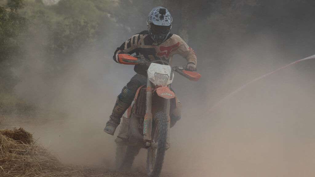 Person riding motocross dirtbike in a dust cloud