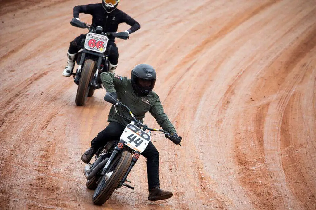 Two men riding motocross on road