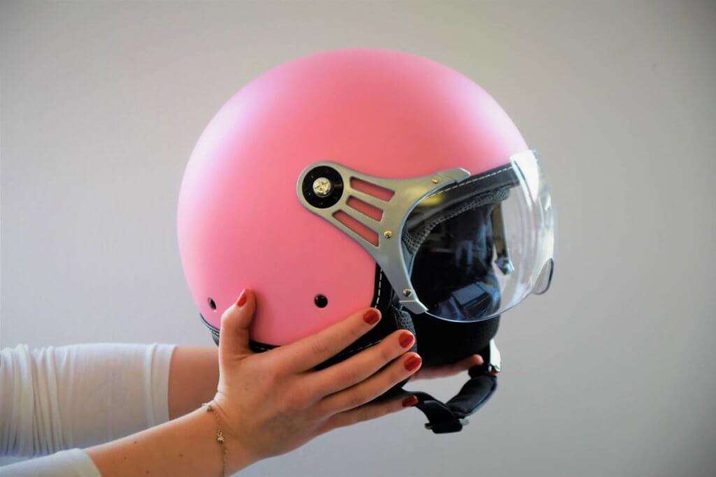 2 hands holding a pink open-face helmet