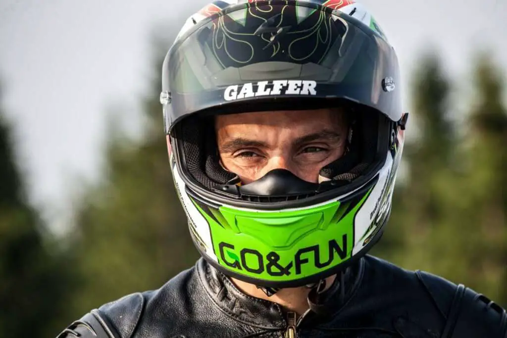 man wearing a multicolored hhelmet with the visor slightly open