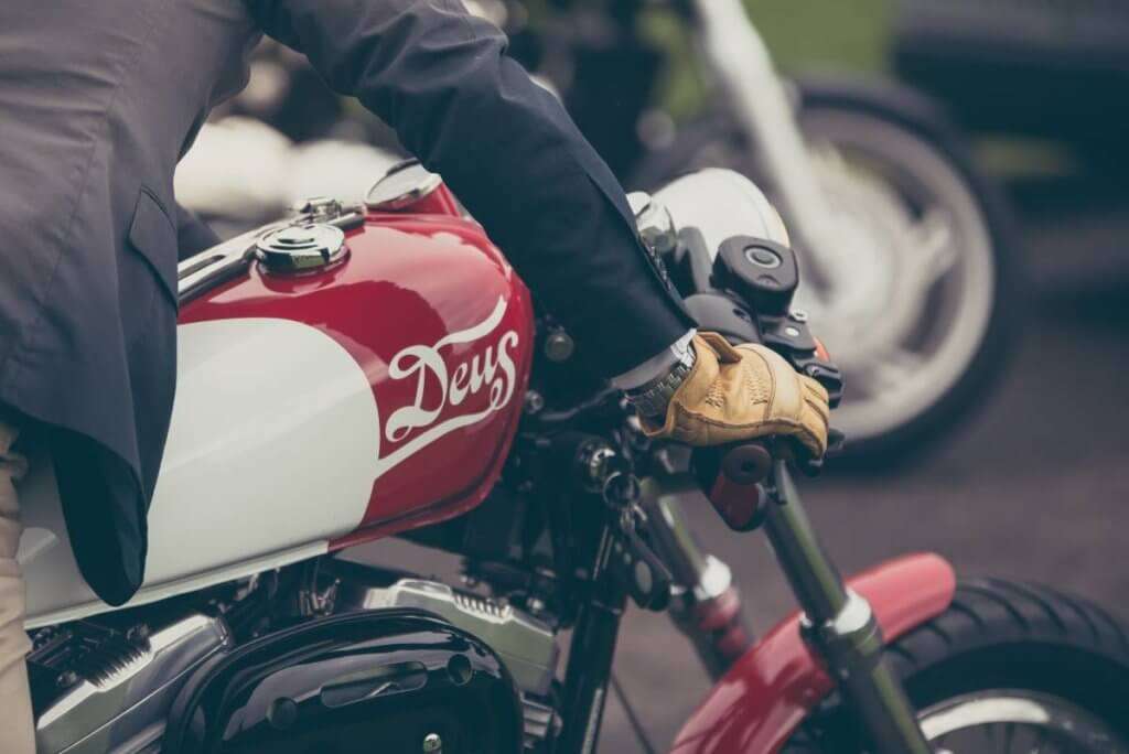 Person riding red and white motorcycle wearing light leather gloves