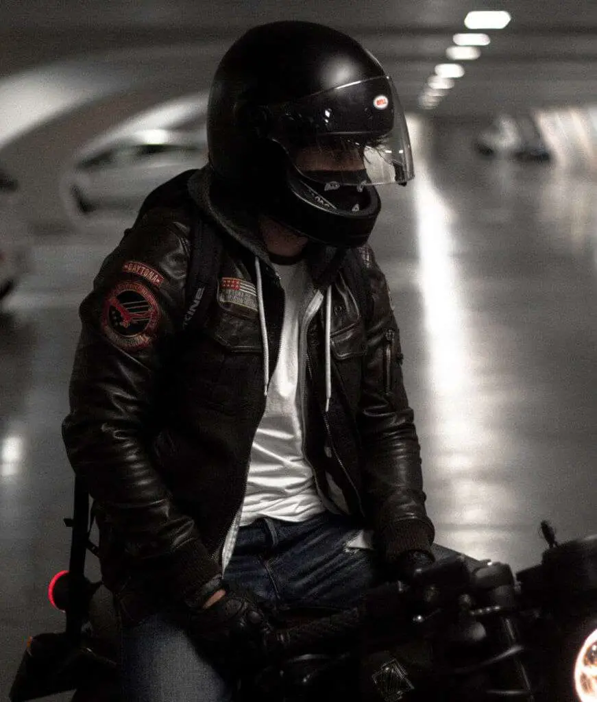 Man in black helmet and black jacket on a motorcycle in a garage