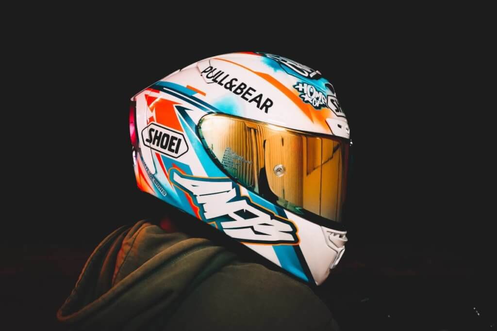 Person wearing a white Shoei Motorcycle helmet with graffiti-style decals