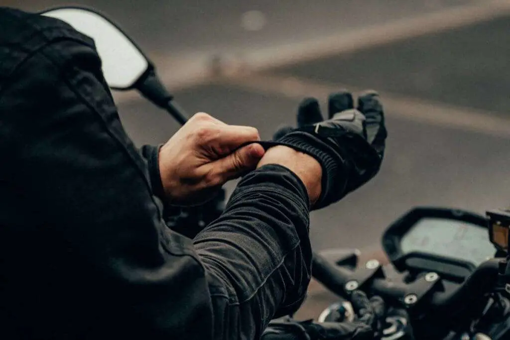 Person putting on black motorcycle gloves