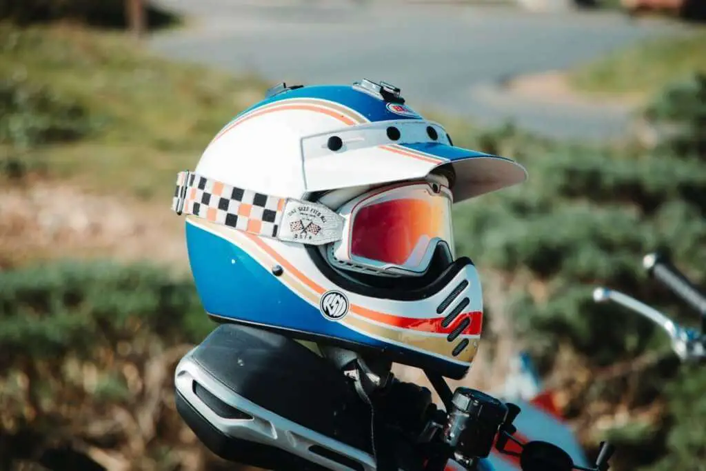 White blue and red motorcycle helmet with glasses on top