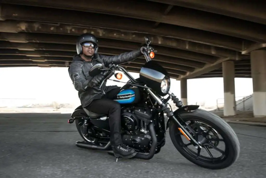 Man riding a motorcycle wearing a gray leather jacket