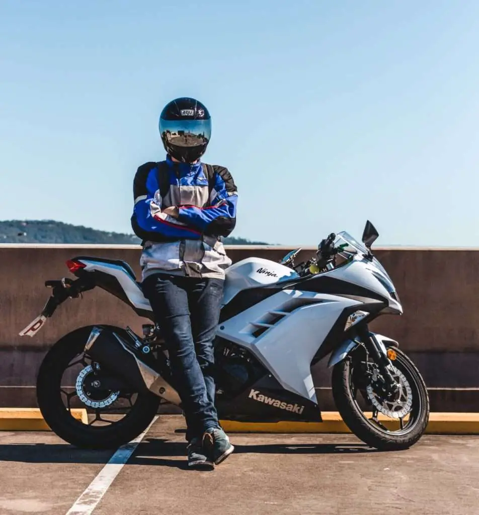 Man wearing mesh jacket next to a white motorcycle