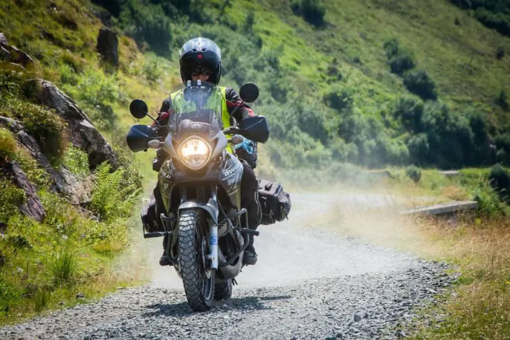 Man riding motorcycle wearing a mesh jacket with a hi-viz vest