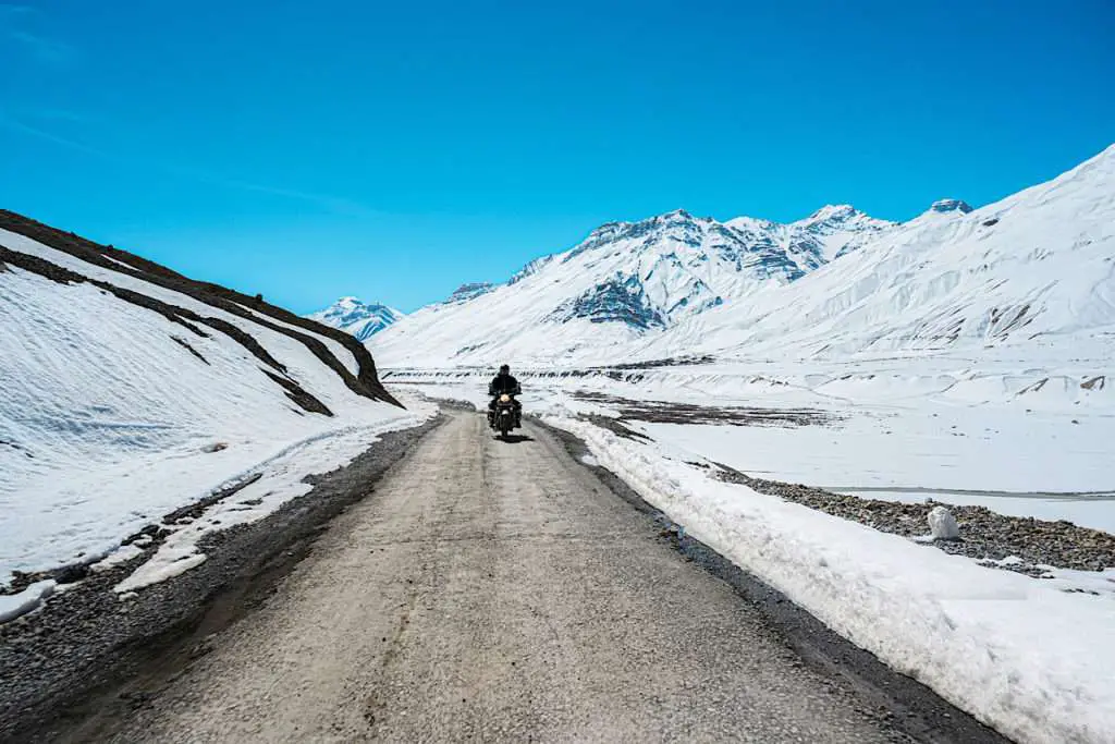 Motorcycle on a mountain road with snow covered mountains in the background