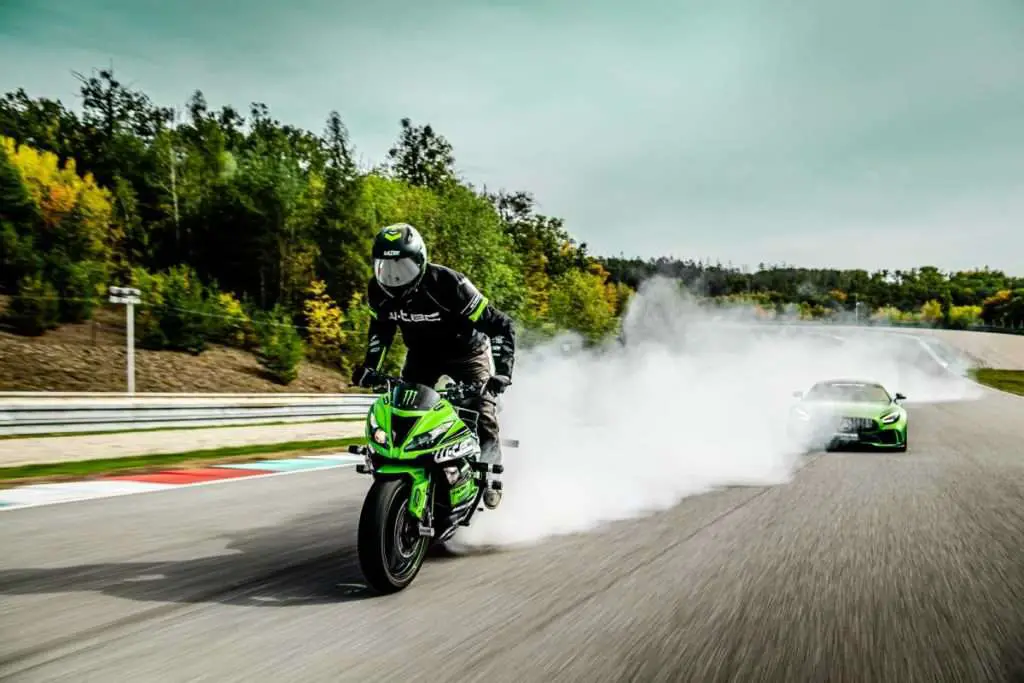 Motorcycle breaking smoke in front of car