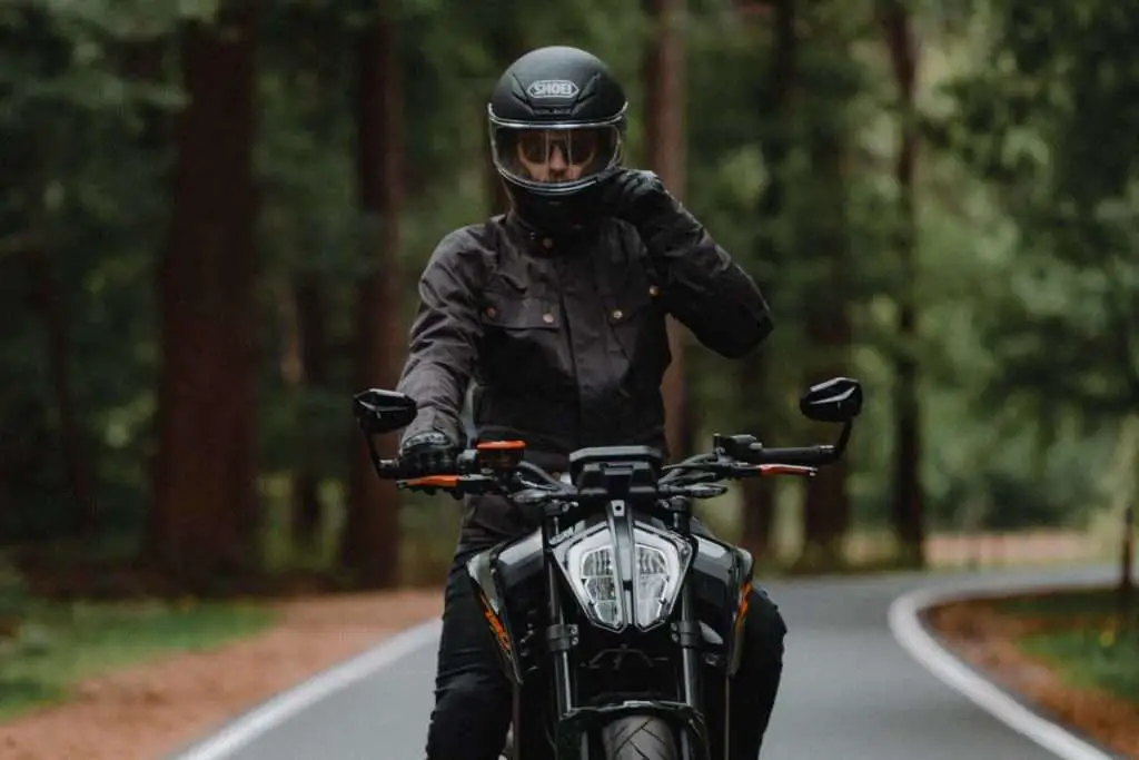 Man in black jacket on a motorcycle wearing a black Shoei helmet