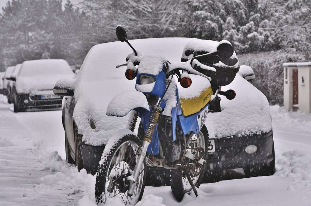 Enduro motorcycle parked on the street and covered by snow