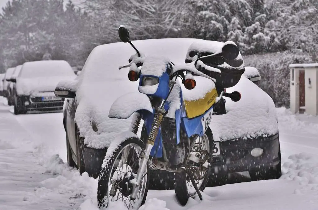 Enduro motorcycle parked on the street and covered by snow