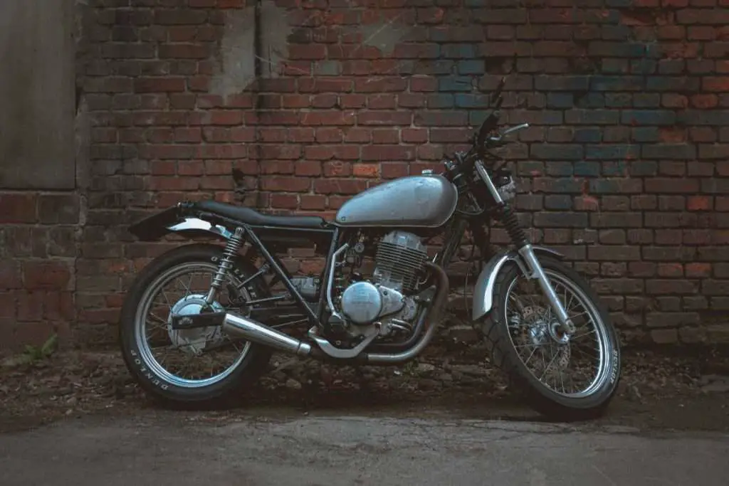 A gray motorcycle in front of a brick wall