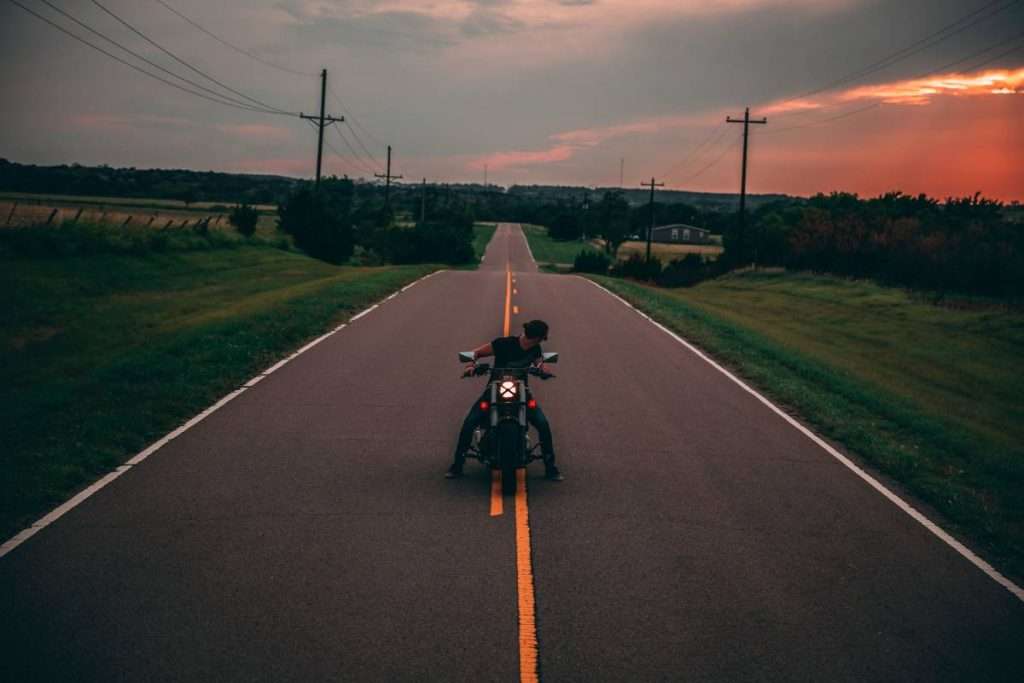 Man on motorcycle at sunset in the middle of the road