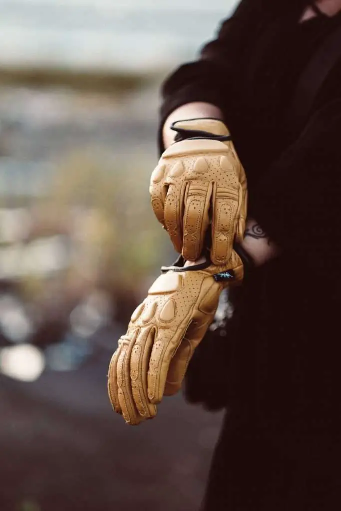 Person adjusting brown motorcycle gloves