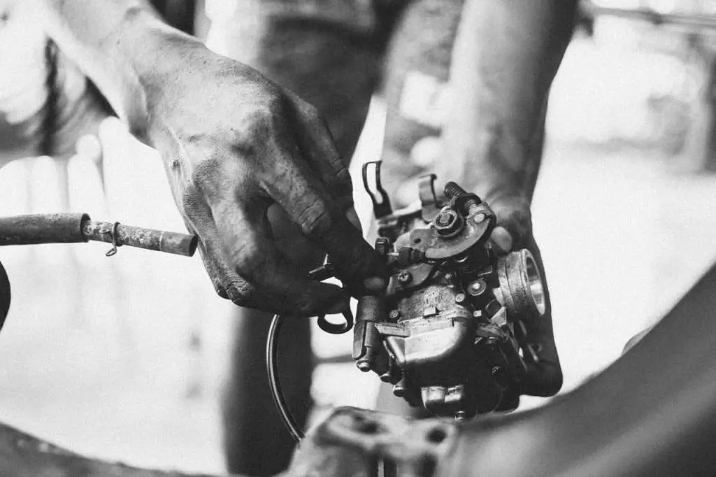 Black & white shot of a person holding a motorcycle carburetor