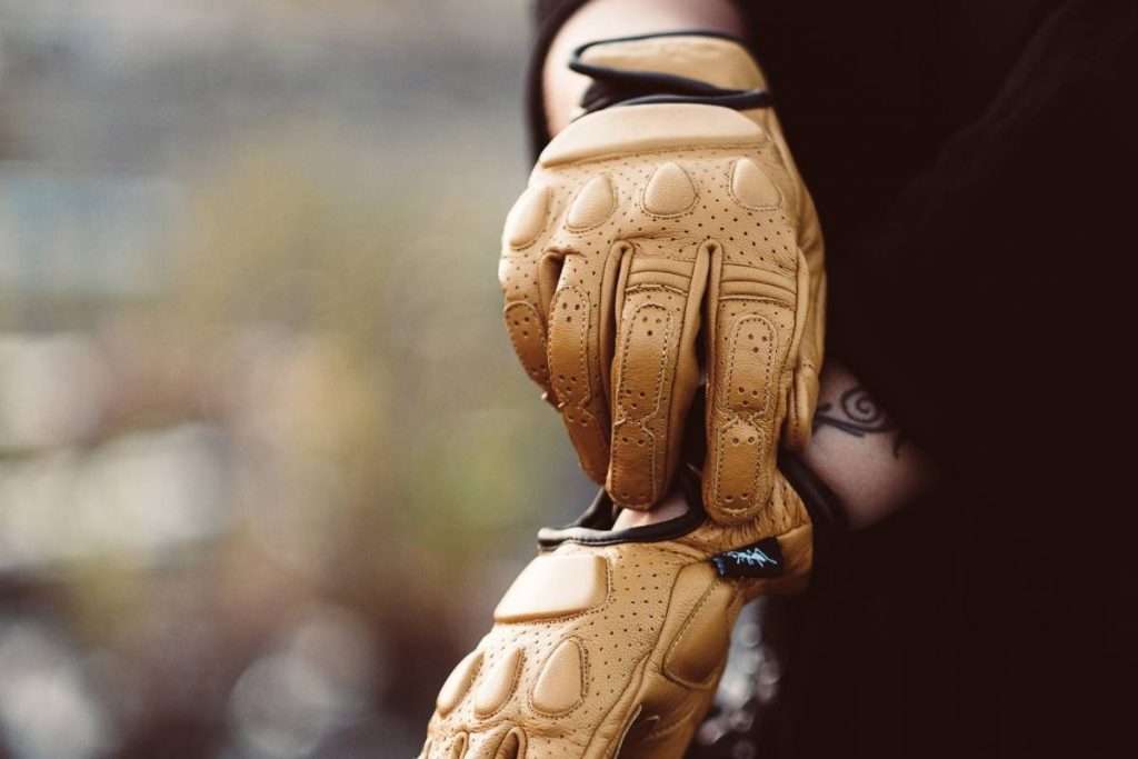 Person putting on brown leather motorcycle gloves